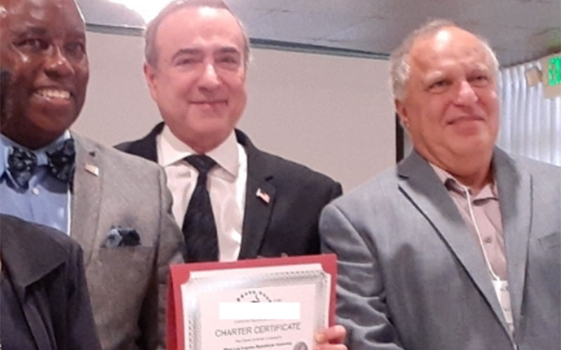 3 men with the man at the center holding an award